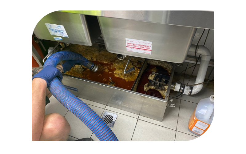 cleaner removing the waste liquids from the grease trap tank